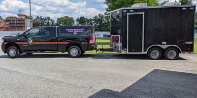 Black emergency response truck towing a trailer in a parking lot.