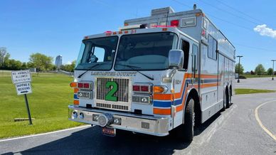 Large white emergency rescue vehicle with orange stripes parked on road.