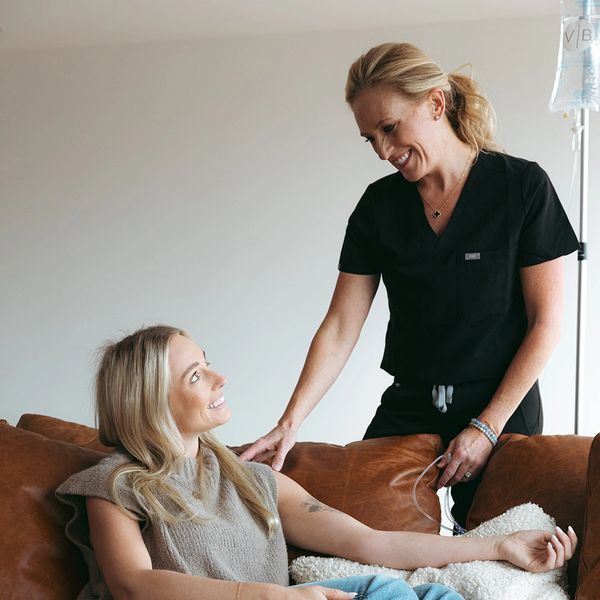 A nurse smiling at a relaxed patient receiving IV treatment at home.