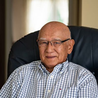 Elderly man wearing glasses and checkered shirt.