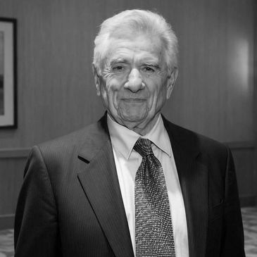 Elderly man in a suit and tie, smiling at the camera.