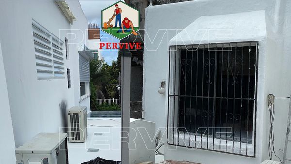 White exterior walls with barred window and air conditioning units.