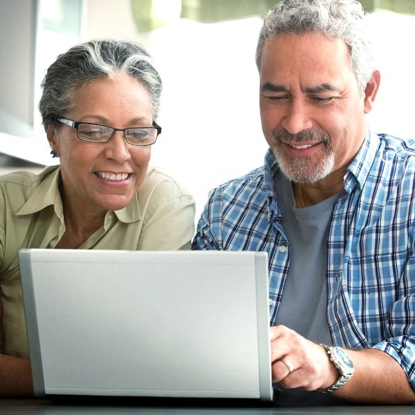 Mature couple reviewing insurance services on a laptop and smiling.