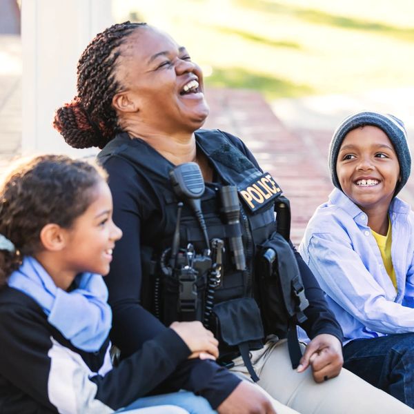 Police officer wearing uniform, sitting outside and laughing with her two children.