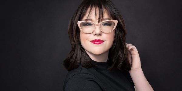 Woman with dark hair and glasses smiling.