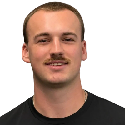 Young man with a mustache smiling, wearing a black shirt.