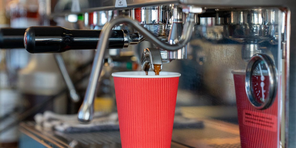 Espresso coffee pouring into a red cup from a coffee machine.