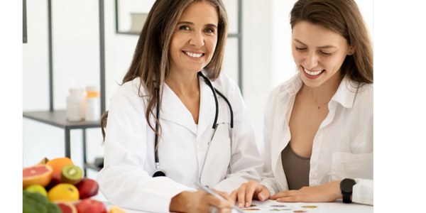A smiling doctor consulting a female patient with fresh fruits on the table.