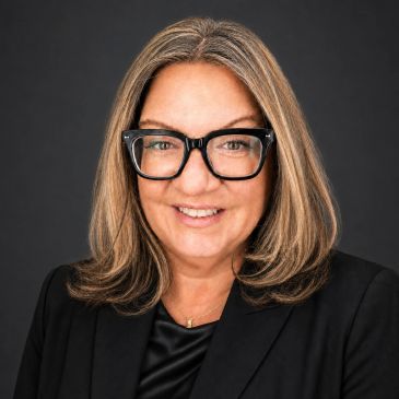 Professional woman with glasses and shoulder-length hair smiling.