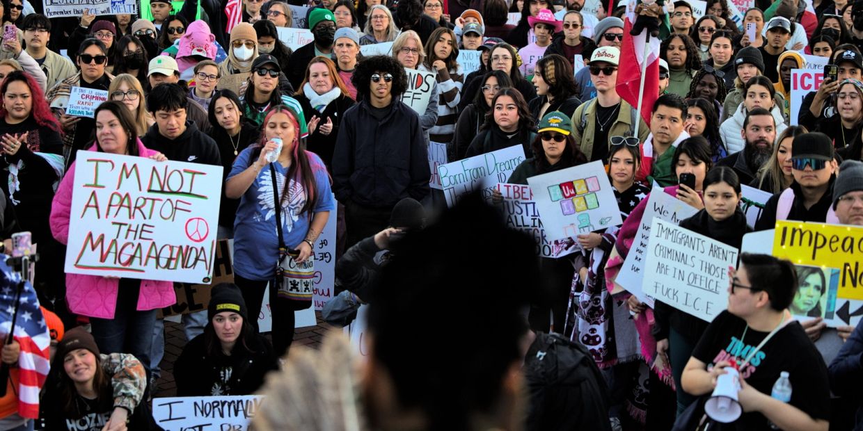Protesters holding signs against ICE and immigration policies.
