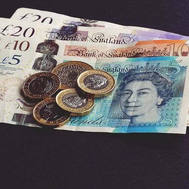 British banknotes and coins on a dark background.