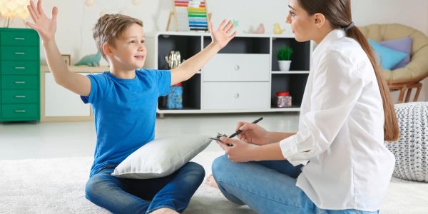 A boy talks animatedly to a woman taking notes in a cozy room.