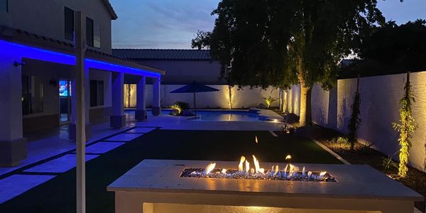 Accent lighting used to enhance appeal of landscape and firepit gathering table 