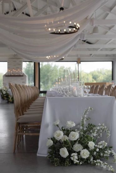 Elegant dining setup with white flowers and candles in a bright, airy room.