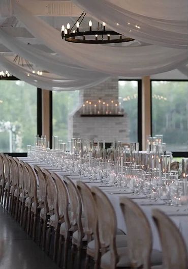 Elegant long dining table set with candles and draped ceiling fabric.