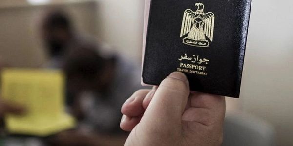 Hand holding an Arabic passport with blurred background.