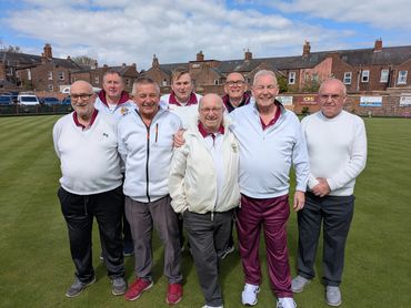 Seven men posing on a bowling green in casual sportswear.