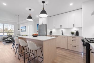 Modern kitchen with wooden cabinets, white countertops, and cozy seating at the island.