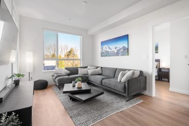 Modern living room with gray sectional sofa and mountain painting.