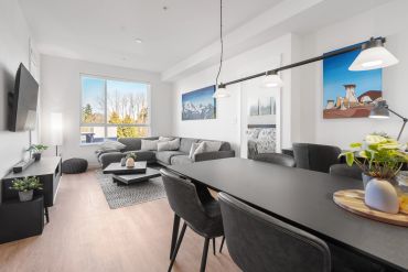 Modern living and dining area with gray furniture and large window.