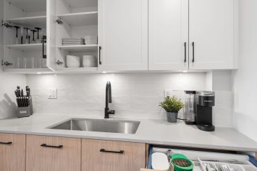 Modern kitchen with white cabinets, stainless steel sink, and Keurig coffee maker.