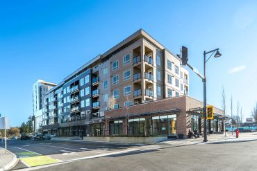Modern multi-story apartment building with balconies on a sunny day.