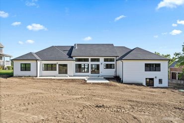 Expansive new build with large windows, hip roof, and elegant white exterior