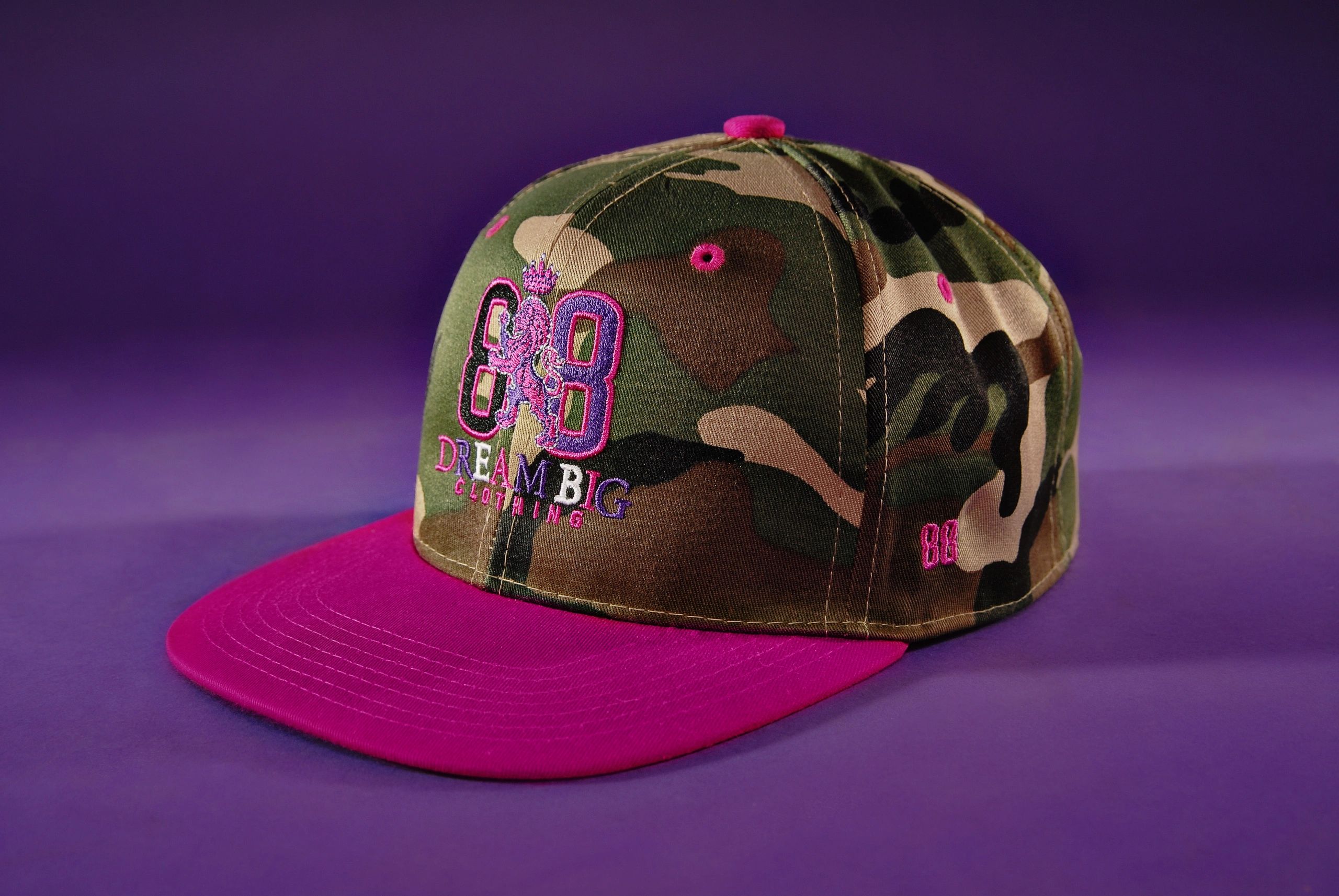 Camouflage and pink snapback cap with "Dream Big" embroidery.