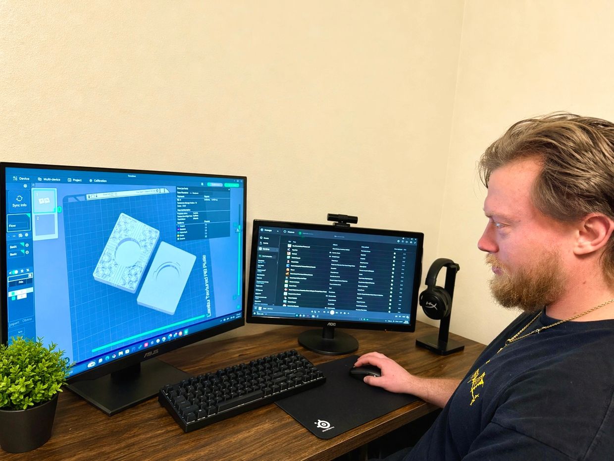 Man working on dual monitors with 3D modeling software.