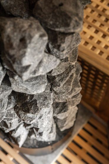 Close-up of sauna stones stacked inside a wooden sauna heater.