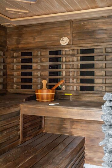 Cozy wooden sauna interior with a bucket and ladle on the bench.
