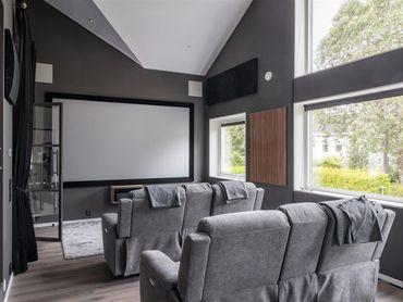 Cozy modern home theater with gray recliners and large screen.