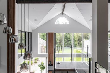 Modern living room with large windows and hanging pendant lights.