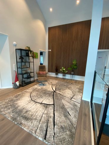 Modern living room with wood-themed rug and cozy armchair.