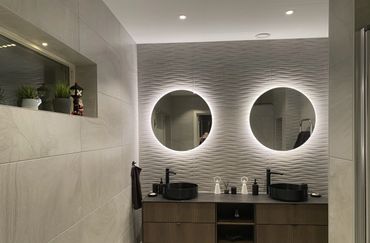 Modern bathroom with dual round mirrors and black sinks.