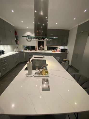 Modern kitchen with a large marble countertop and grey cabinetry.