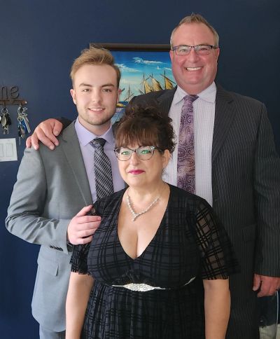 Three dressed-up people posing and smiling indoors.