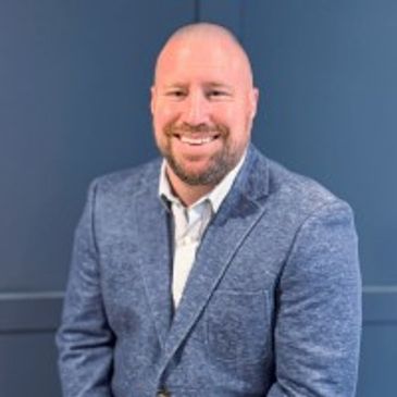 Smiling man wearing a blue blazer.