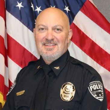 Police officer in uniform with American flag background.