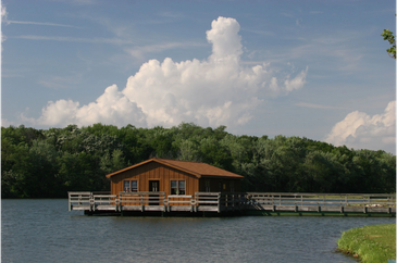 Wooden house on stilts over water with cloudy sky.