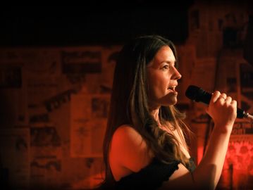 Woman speaking into a microphone on stage.