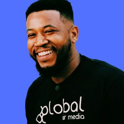 Smiling man wearing a black Global Air Media shirt against a blue background.