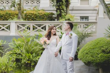 Bride and groom holding hands in a garden setting.