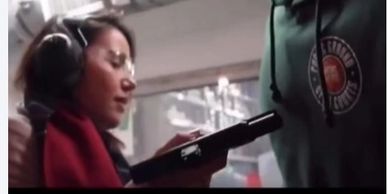 Woman wearing protective ear gear aiming a handgun at a target range.
