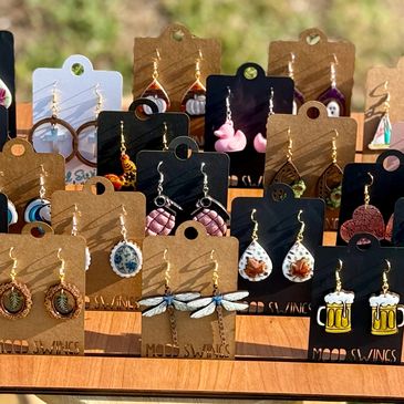 Display of colorful handmade earrings on cardboard holders outdoors.
