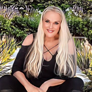 Woman with long blonde hair sitting outdoors and smiling.