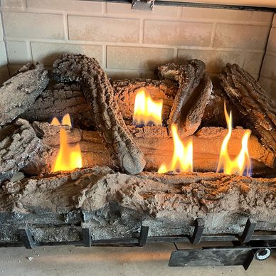 Artificial logs burning with bright flames in a fireplace.