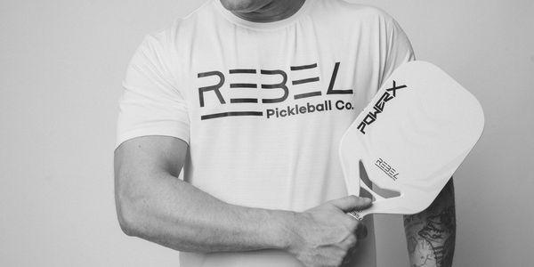 man in black and white holding a rebel pickleball paddle