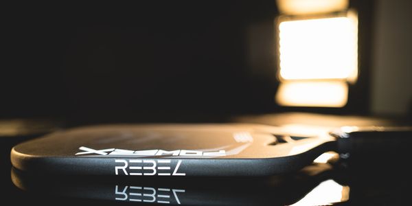 Close-up of a tennis racket with 'Rebel' branding.