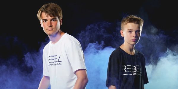 two young men surrounded by smoke in rebel pickleball shirts